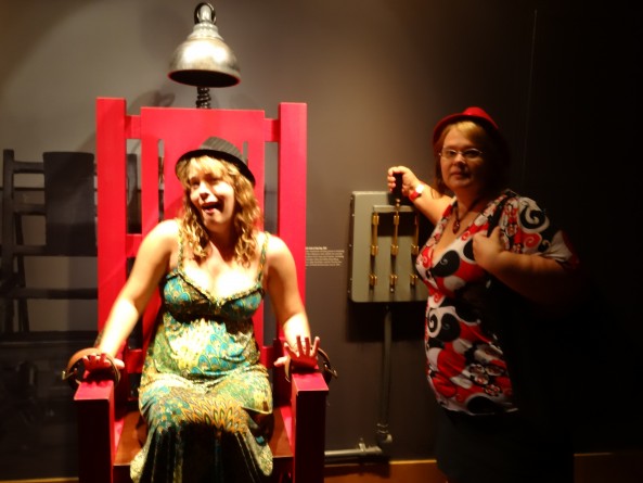 girl sitting in fake electric chair and woman pulling the lever at the mob museum in las vegas