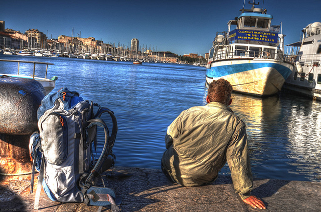 backpacker sitting on the dock of a bay